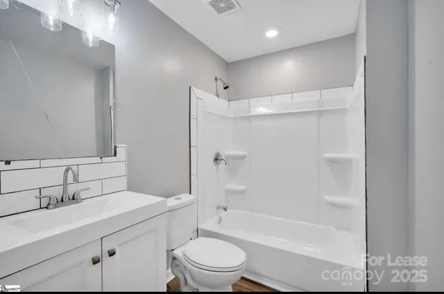 a bathroom with a bathtub shower sink vanity mirror and toilet