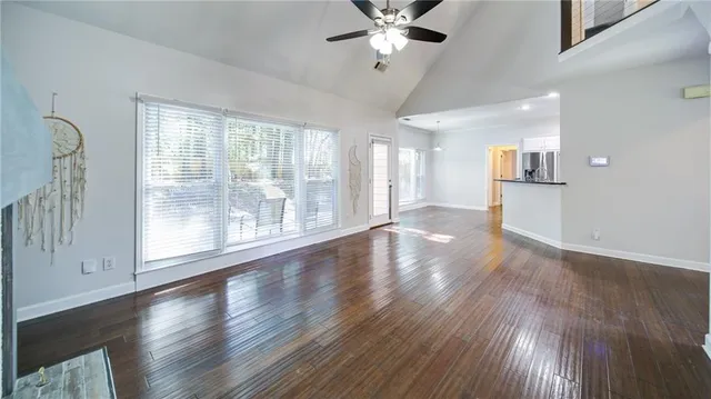 a view of an empty room with wooden floor and a window