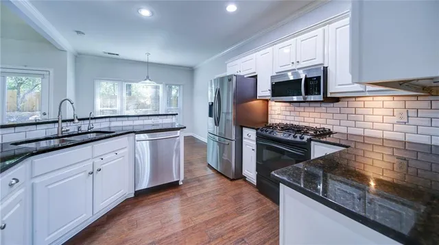 a kitchen with stainless steel appliances granite countertop a sink stove and microwave