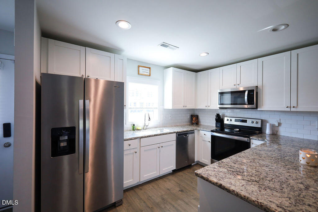 230 South Raleigh Street Angier, NC 27501 - Photo 6 of 38 a kitchen with stainless steel appliances granite countertop a refrigerator a sink a stove a microwave and wooden cabinets