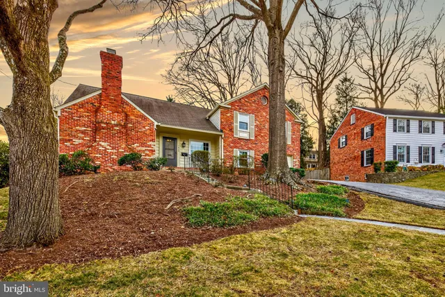 a front view of a house with a yard and many trees