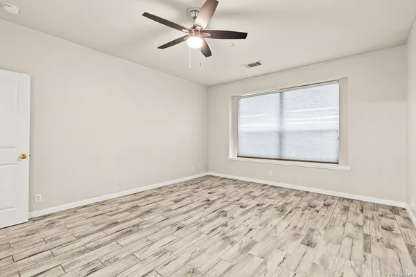 a view of empty room with wooden floor and fan