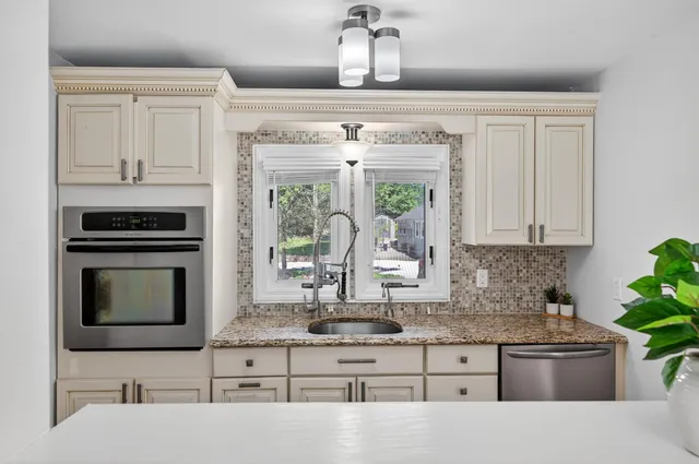 a kitchen with granite countertop a stove sink and cabinets