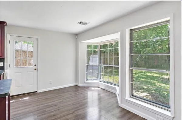 a view of an empty room with wooden floor and windows