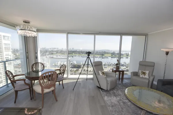 a living room with furniture large windows and wooden floor