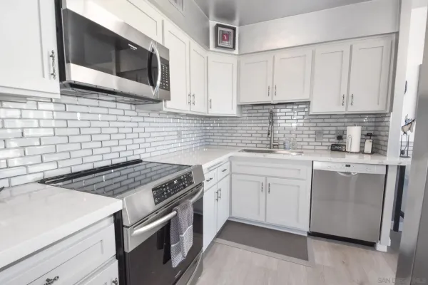 a kitchen with stainless steel appliances granite countertop white cabinets a microwave a sink and dishwasher