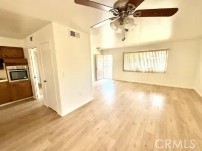 a view of a kitchen with wooden floor a ceiling fan and windows