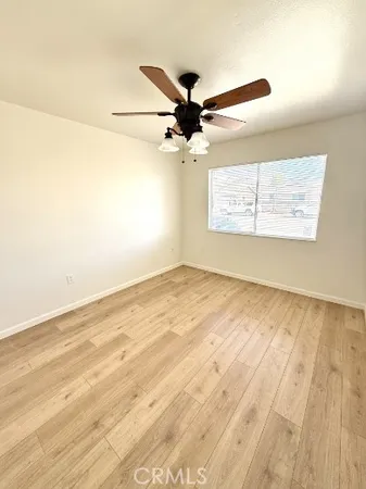 an empty room with wooden floor fan and windows
