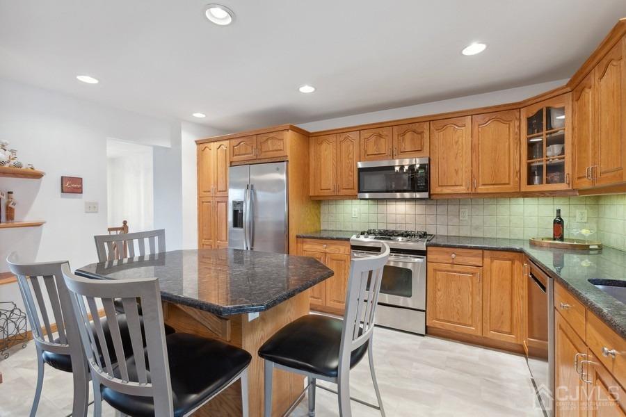34 South Cliff Road Colonia, NJ 07067 - Photo 4 of 29 a kitchen with stainless steel appliances granite countertop a stove a refrigerator a kitchen island a table and chairs