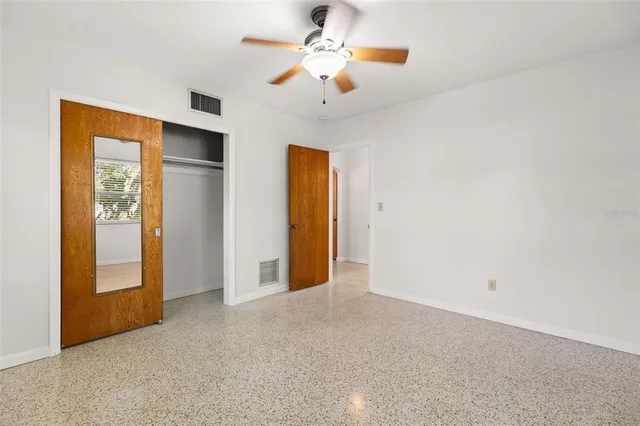 an empty room with windows and chandelier fan