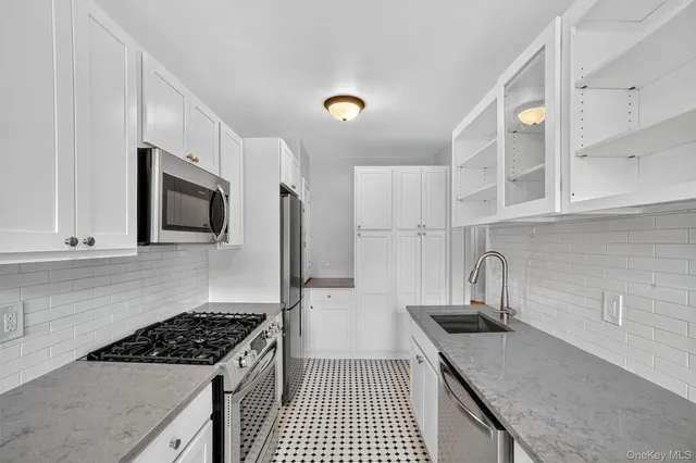 a kitchen with granite countertop a sink stove and refrigerator