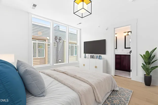 a bedroom with a bed television window and potted plant