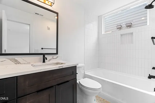 a bathroom with a bathtub sink vanity mirror and toilet
