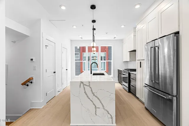 a large kitchen with stainless steel appliances kitchen island granite countertop a refrigerator and a sink