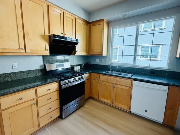 a kitchen with granite countertop a sink a stove and cabinets