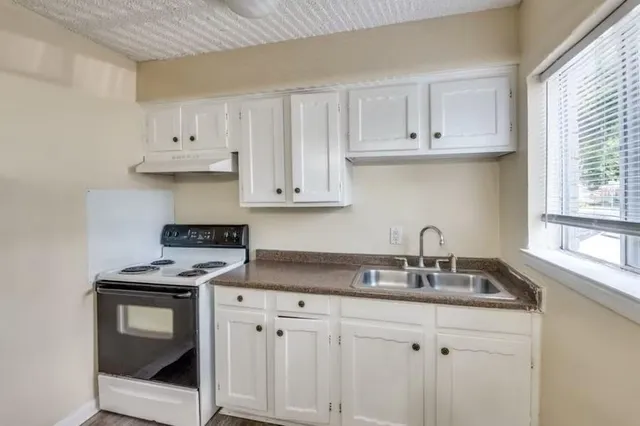 a kitchen with granite countertop a sink a stove and cabinets