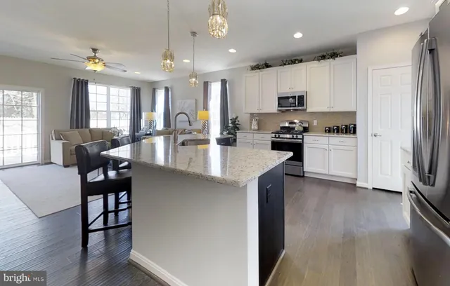 a kitchen with a refrigerator a stove top oven a sink dishwasher and white cabinets with wooden floor