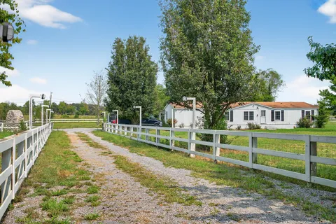 a kitchen with stainless steel appliances kitchen island granite countertop a refrigerator a stove top oven and a dining table with wooden floor