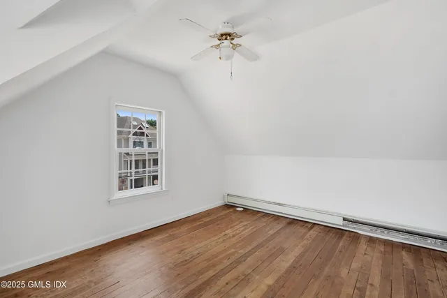 an empty room with wooden floor chandelier fan and windows