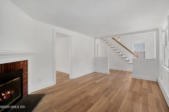 a view of empty room with wooden floor and fireplace