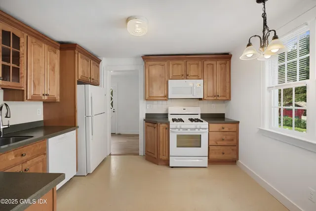 a kitchen with stainless steel appliances granite countertop a refrigerator a stove a sink dishwasher and white cabinets with wooden floor