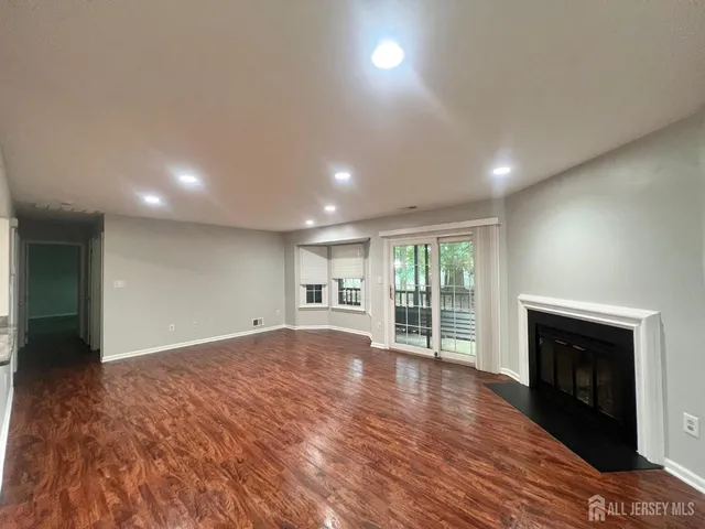 an empty room with wooden floor fireplace and windows