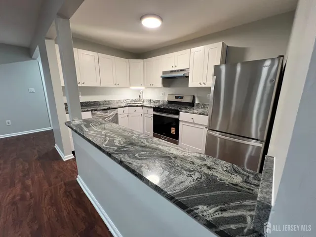 a kitchen with stainless steel appliances granite countertop a refrigerator a stove and a sink