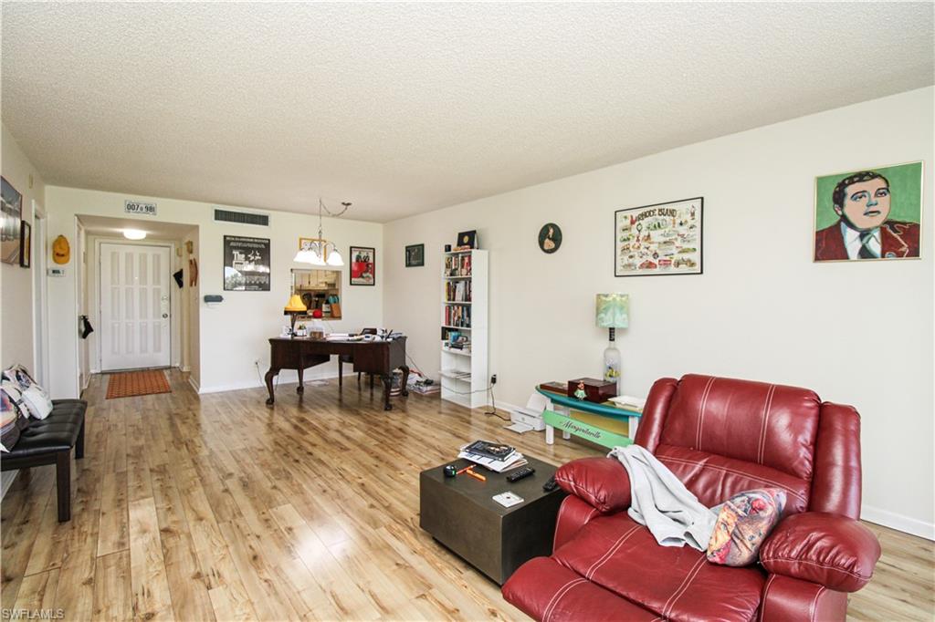 41 High Point Circle South, Unit 303 Naples, FL 34103 - Photo 19 of 39 a living room with furniture and wooden floor