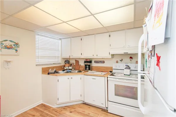 a kitchen with stainless steel appliances a white refrigerator stove a sink and white cabinets