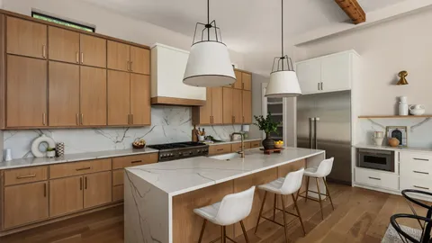 a kitchen with stainless steel appliances kitchen island granite countertop a table chairs in it and white cabinets