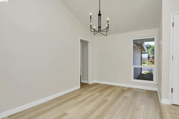 a view of an empty room with wooden floor fireplace and a window