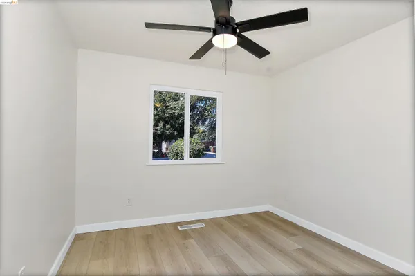 an empty room with a window and a fan