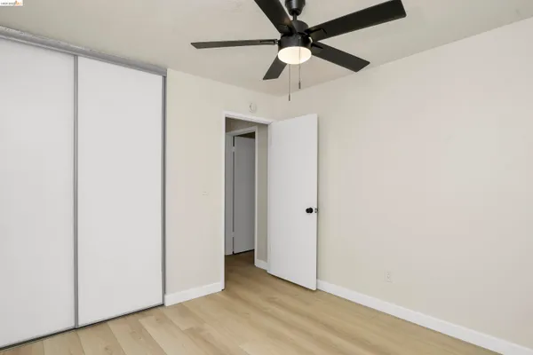 an empty room with a ceiling fan and wooden floor