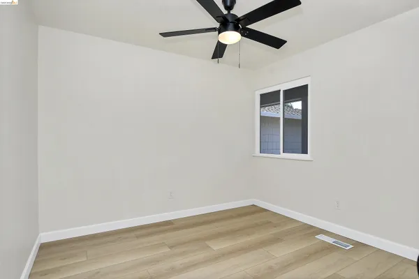 an empty room with a window and ceiling fan