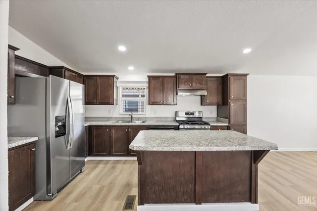 a kitchen with stainless steel appliances granite countertop a refrigerator a sink a stove a microwave and island