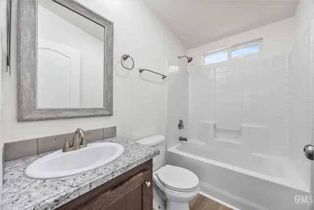 a bathroom with a granite countertop sink a toilet a mirror and shower