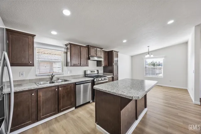 a kitchen with stainless steel appliances granite countertop a sink stove and refrigerator