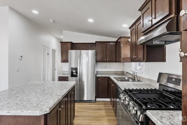 a kitchen with stainless steel appliances granite countertop a stove a refrigerator a sink and dishwasher