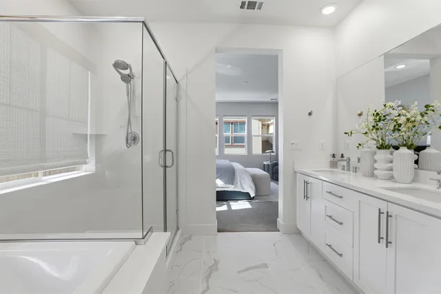 a spacious bathroom with a double vanity sink a large mirror a shower and bathtub