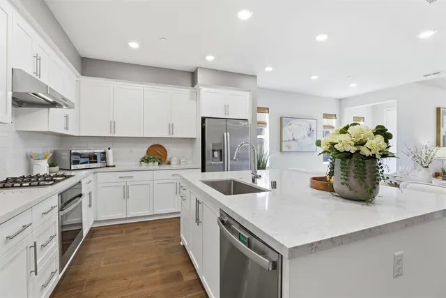 a kitchen with a sink dishwasher a stove and white cabinets