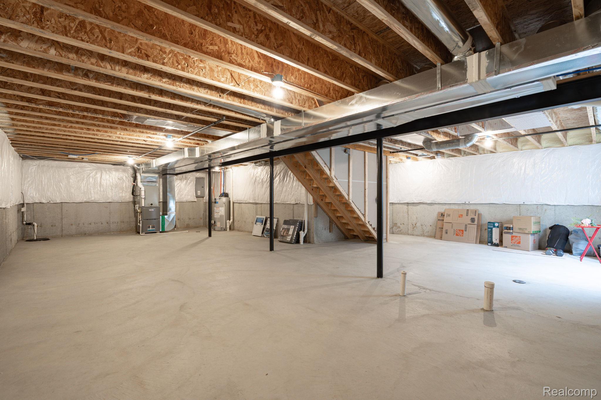 48904 Carnegie Way Macomb, MI 48042 - Photo 33 of 34 Unfinished basement featuring an open concrete floor, exposed wood ceiling joists, and concrete foundation walls