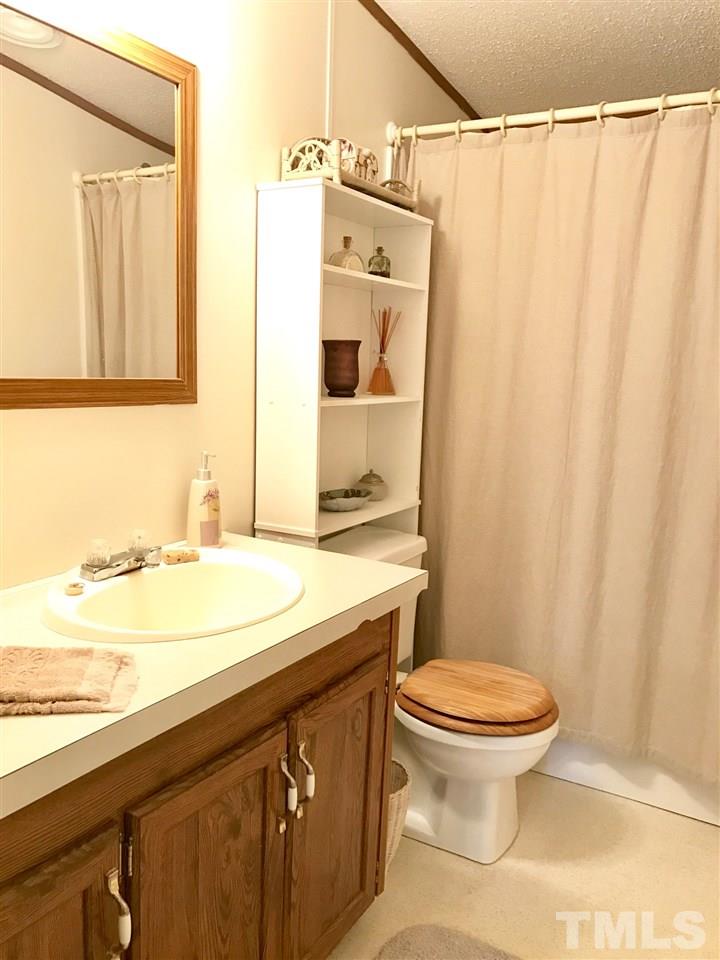 6916 Matthews Road Durham, NC 27712 - Photo 8 of 24 a bathroom with a granite countertop sink toilet and shower