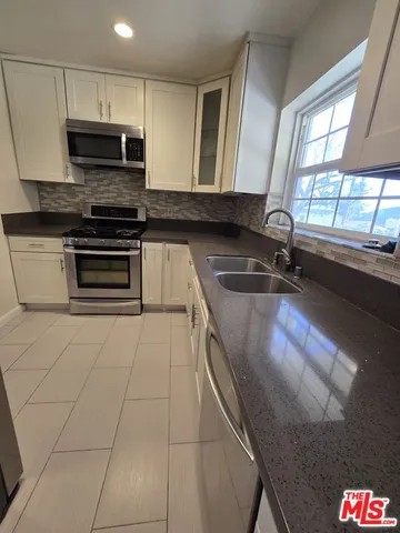 a kitchen with granite countertop a stove a sink and a microwave