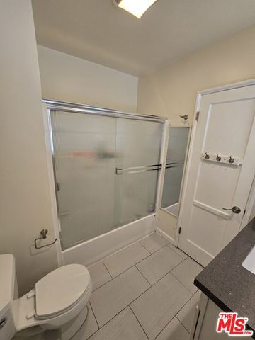 a bathroom with a granite countertop shower and a toilet