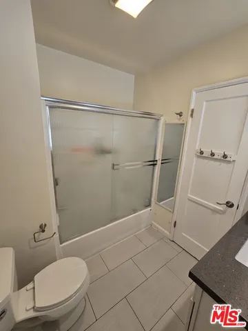a bathroom with a granite countertop shower and a toilet