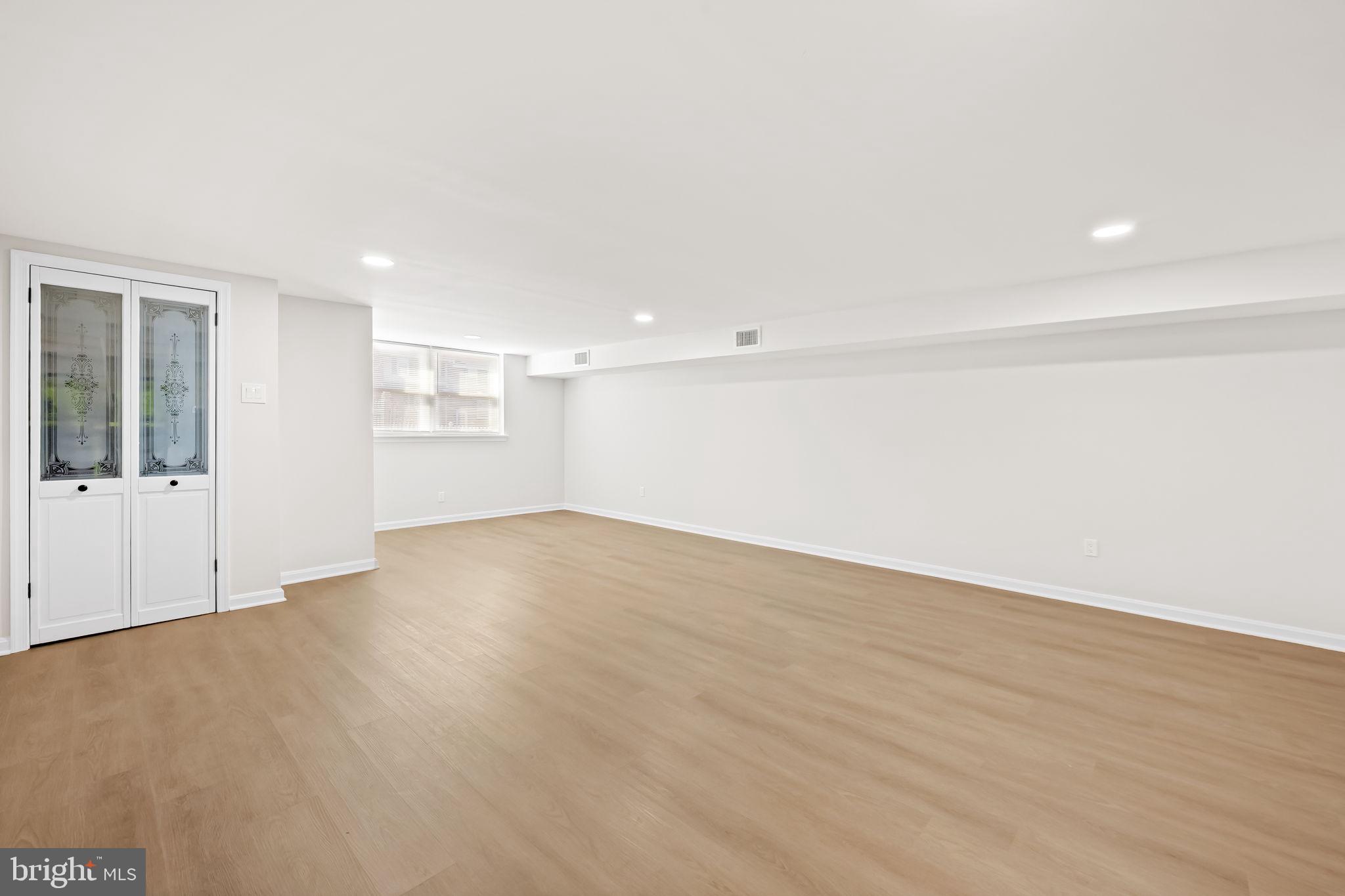 5613 Chelwynd Road Baltimore, MD 21227 - Photo 15 of 38 a view of an empty room with wooden floor and windows