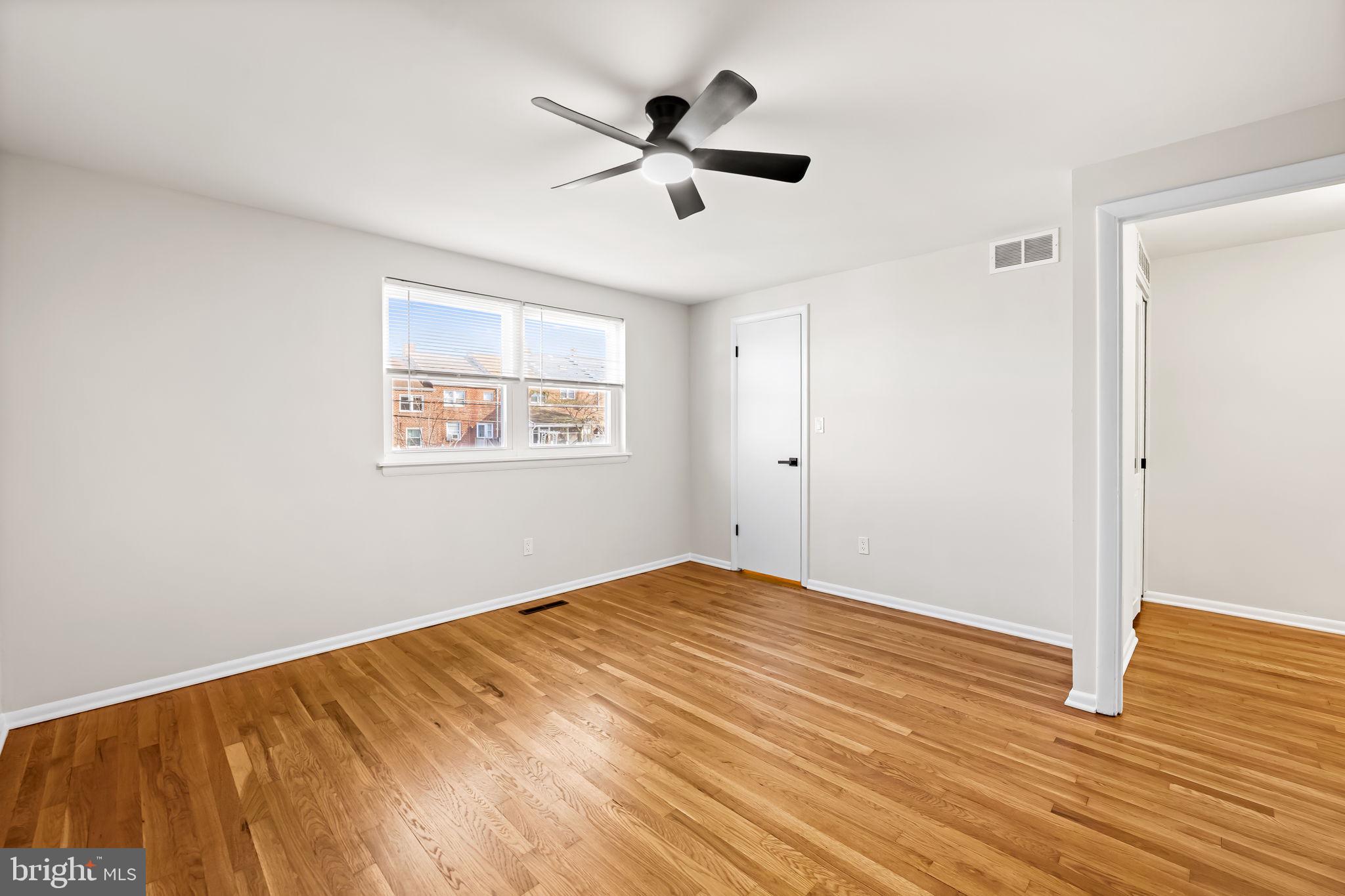 5613 Chelwynd Road Baltimore, MD 21227 - Photo 25 of 38 a view of empty room with wooden floor and fan