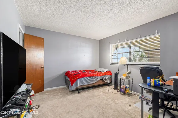 a bedroom with a bed and a flat tv screen next to a window
