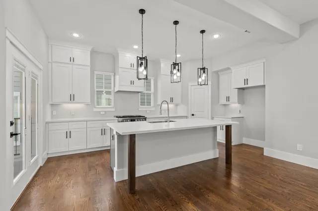a kitchen with white cabinets appliances and wooden floor