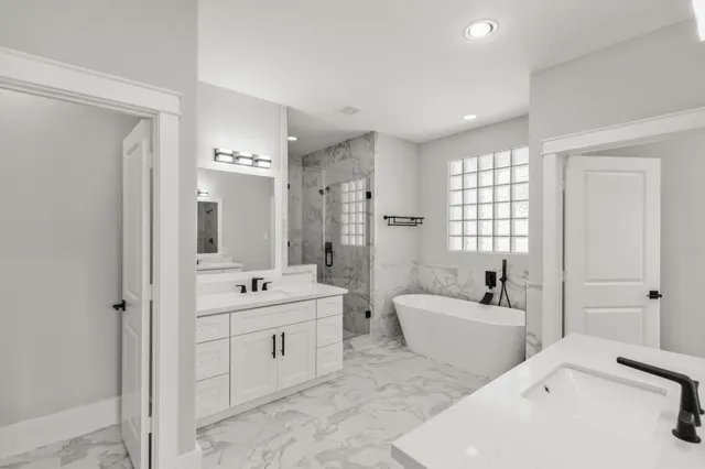 a spacious bathroom with double vanity a sink a mirror a bathtub and shower